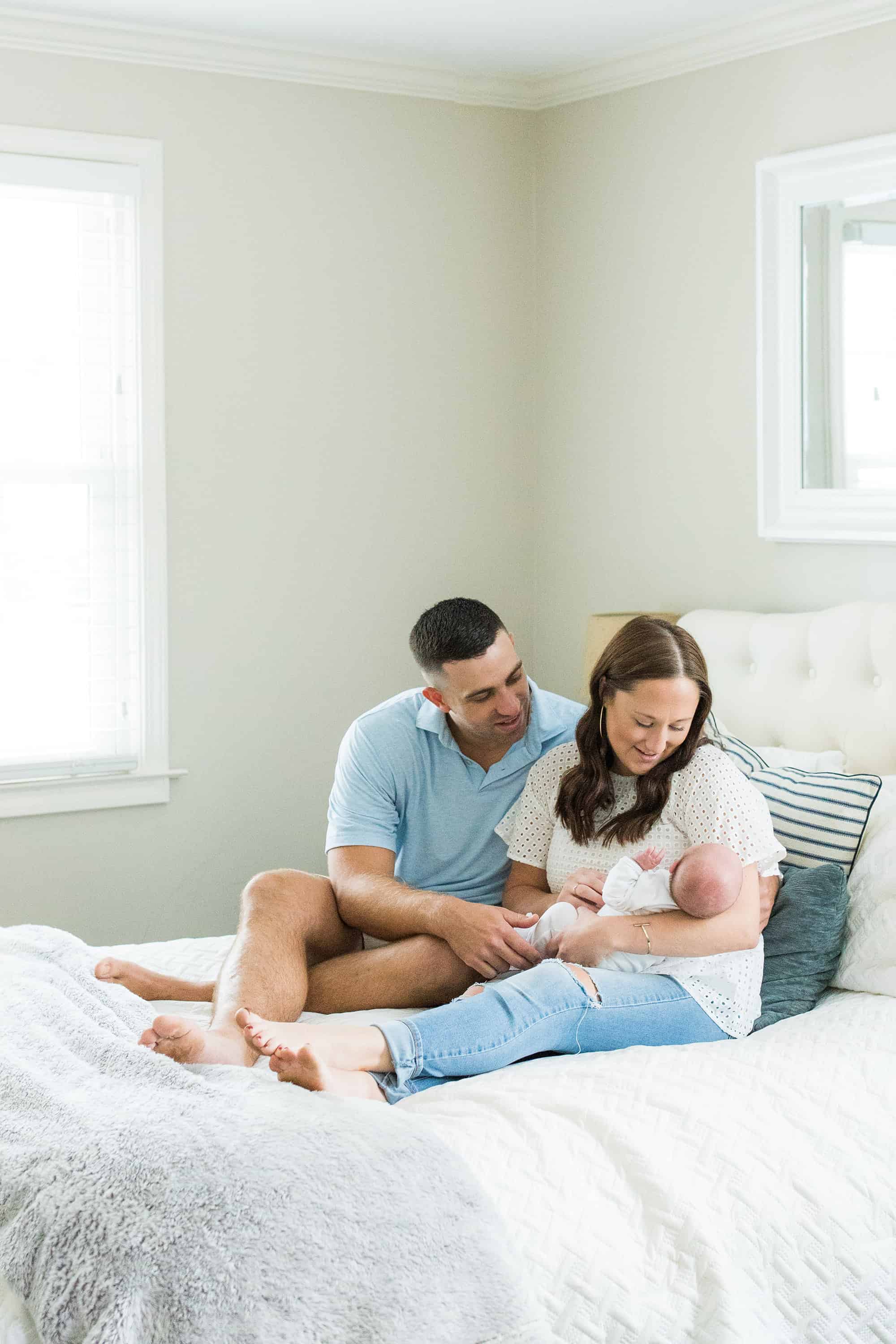 Mom and dad with baby on bed Greenville newborn photographer