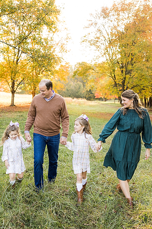 Family walking hand in hand in field in fall