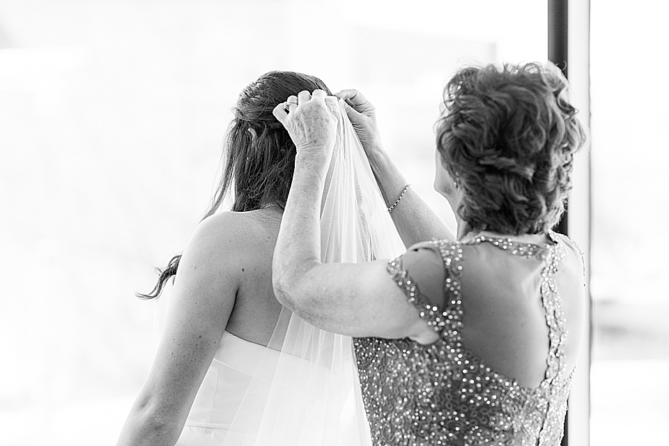 mother of bride placing veil in brides hair